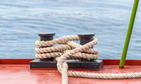 Zwei Poller an einer Hafenmauer. Mit einem dicken Tau wurde ein Schiff fachgerecht festgemacht und liegt sicher im Hafen.