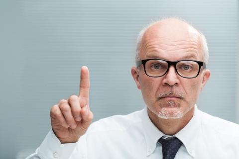 Älterer Mann hebt den Zeigefinger: Achtung!