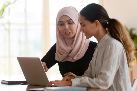 Frau mit Hijab erläutert einer Frau ohne Hijab die Voraussetzungen für eine Anstellung im Öffentlichen Dienst