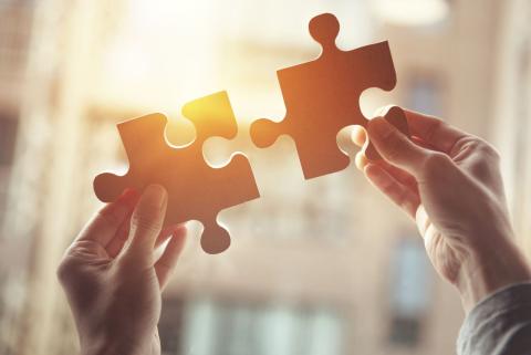 Hände halten zwei ineinandergreifende Puzzleteile hoch