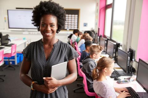 Junge Schwarze Lehrerin unterrichtet Grundschüler im Computerraum