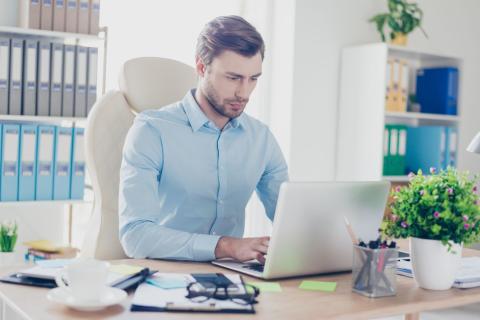 Junger Beamter arbeitet in seinem Büro am Laptop