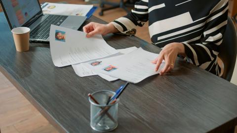 Weibliche Fachkraft sortiert auf ihrem Schreibtisch Lebensläufe