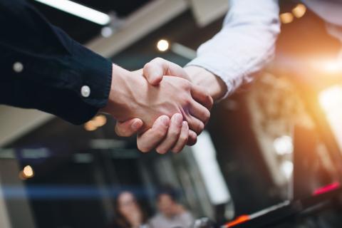 Zwei Menschen schütteln sich in einem Büro die Hand