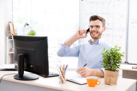 Männliche Fachkraft arbeitet am Schreibtisch und telefoniert