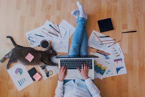 Person arbeitet umgeben von Unterlagen im Homeoffice